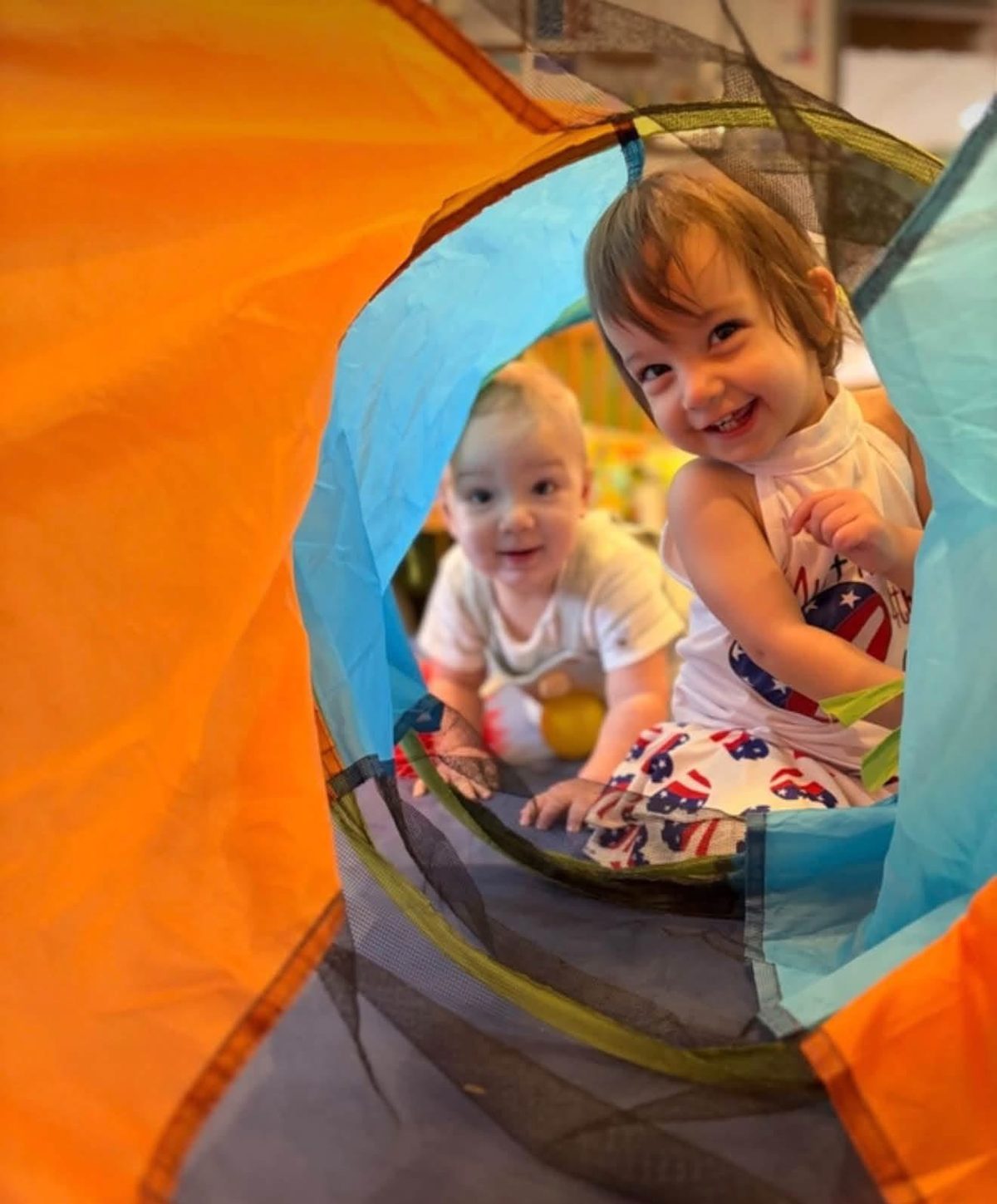 Two little ones peeking out of the play tunnel